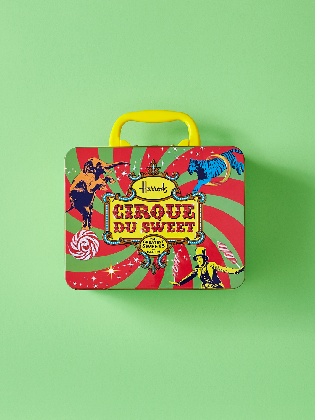 Eine Dose im Stil einer Lunchbox für Süßigkeiten. Ein Design im Zirkusstil für Harrods. Die Dose hat einen Klappdeckel mit Clip und einen Tragegriff.