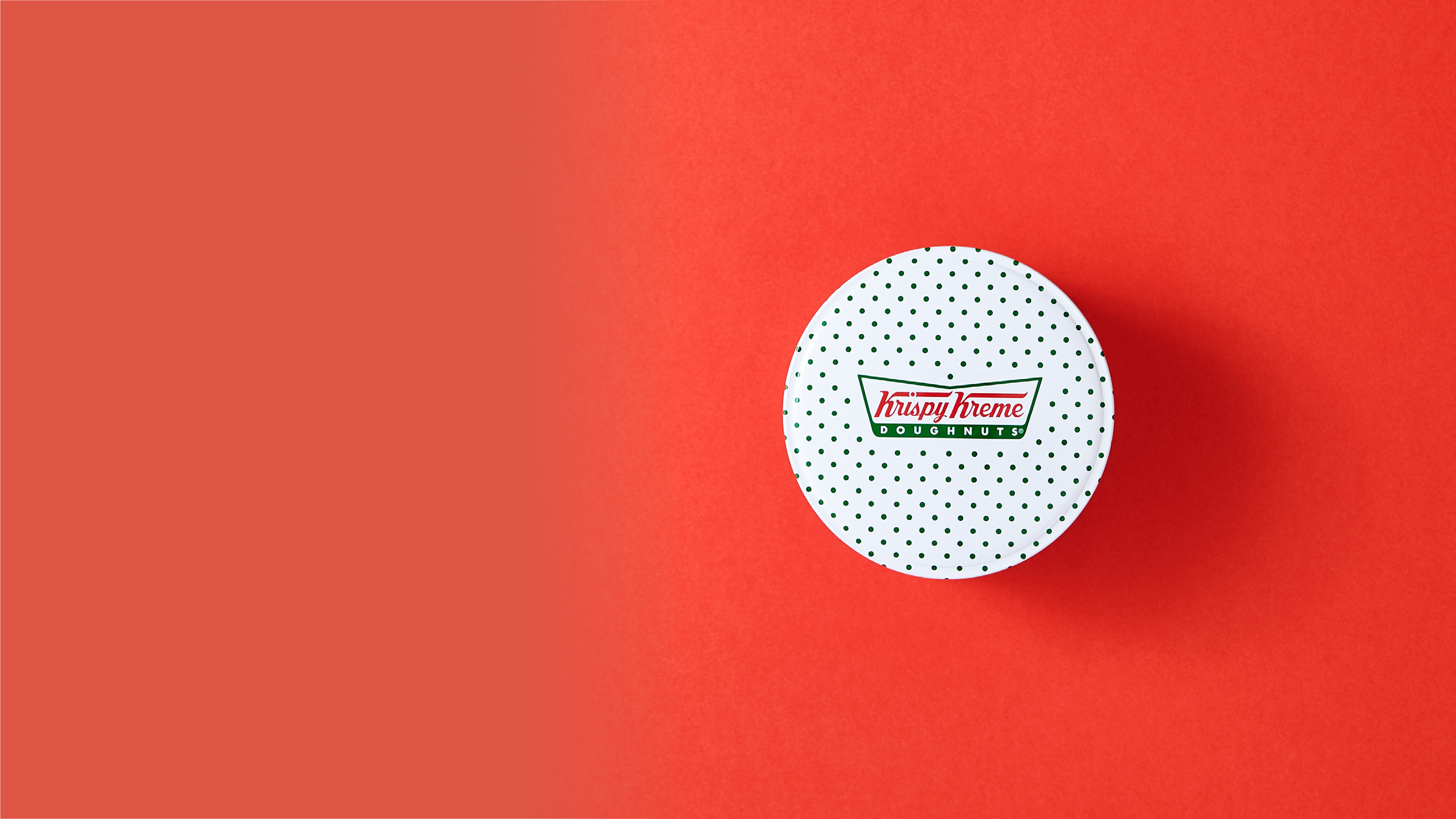 Eine Donut-Dose von Krispy Kreme vor rotem Hintergrund.
