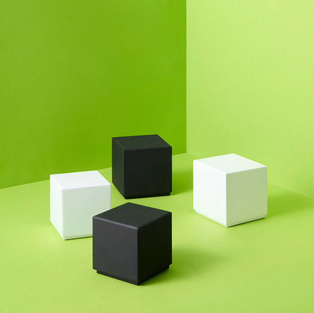 Weiße und schwarze stabile Geschenkboxen auf grünem Hintergrund 
